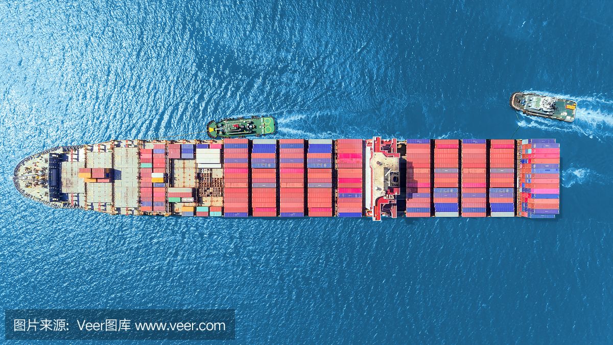 拖船拖着集装箱船到海港卸货集装箱到集装箱仓库物流进出口,航运或运输概念。
